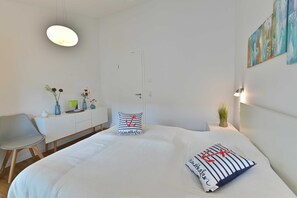 Ein modernes Schlafzimmer mit einem großen Bett, einem Nachttisch, einem Sessel und einem Schreibtisch.