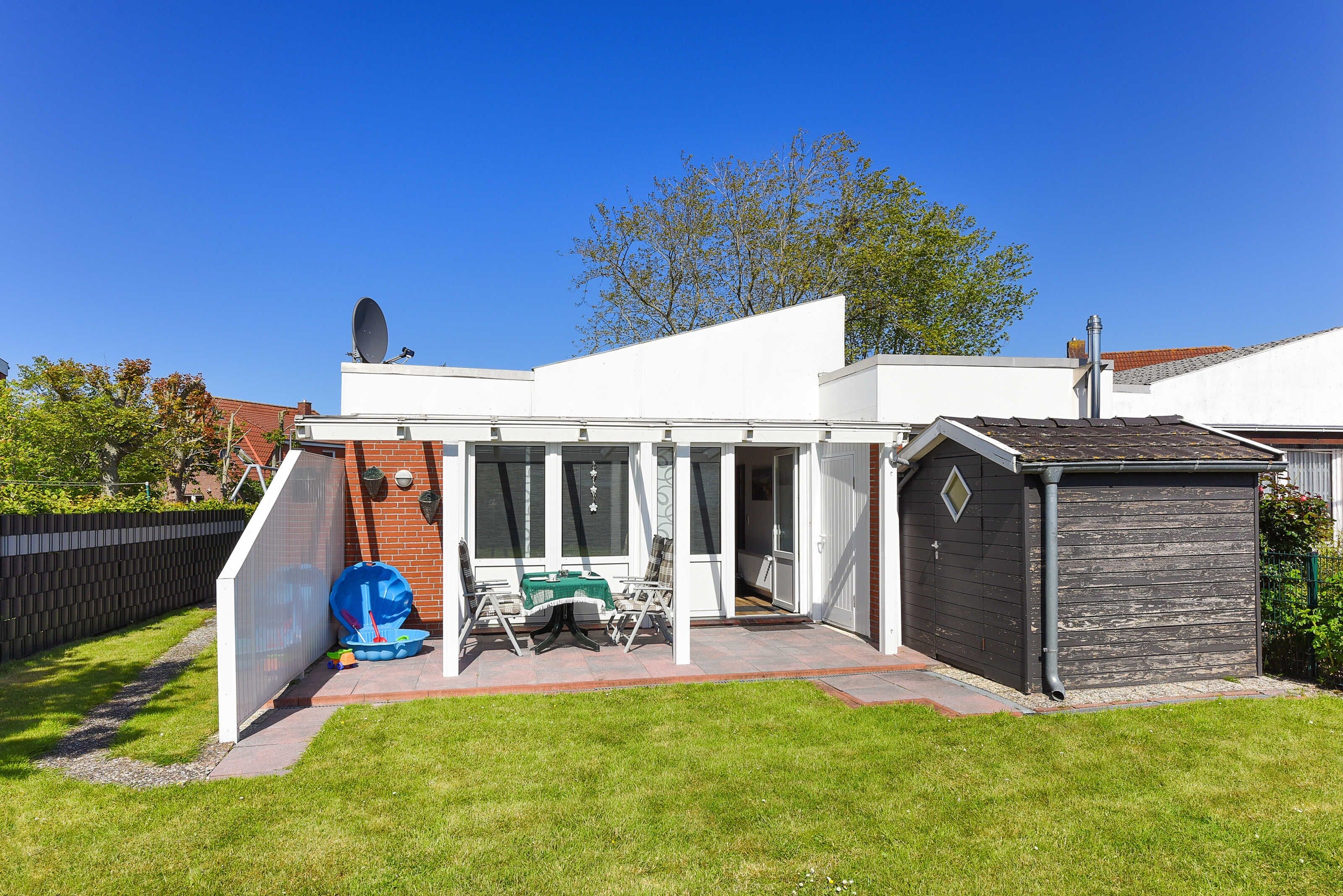 A modern house with a patio, a shed, and a fenced backyard.