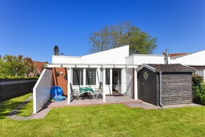 Et moderne hus med terrasse, skur og en lukket have.