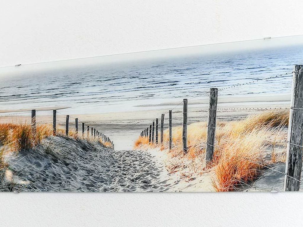 A beach scene with a wooden fence and sand dunes.