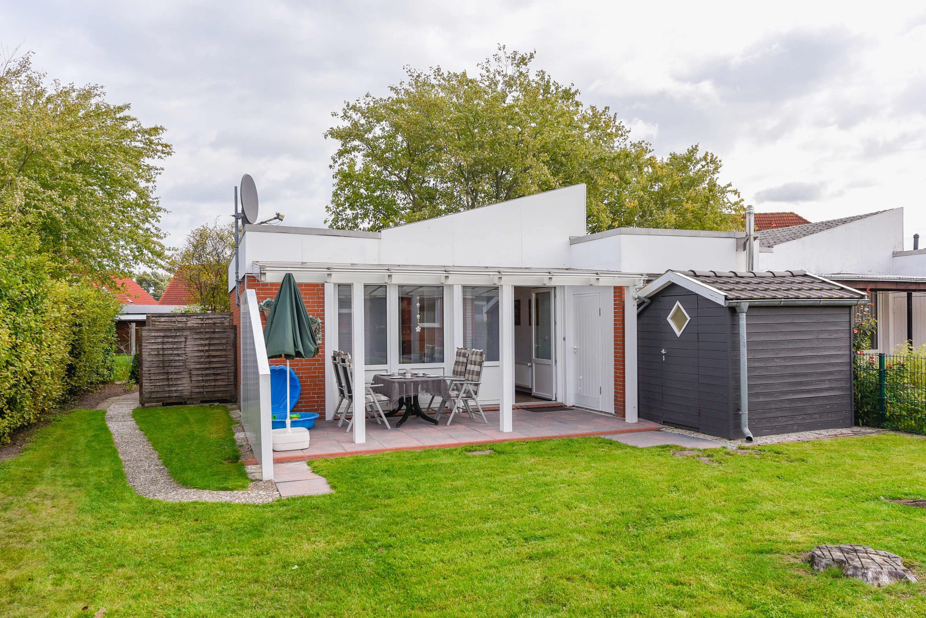 A modern house with a patio, a play area, and a shed.