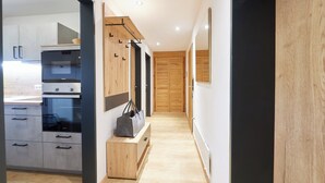 Een moderne keuken met inbouwapparatuur, een houten bankje en een gang naar een deur.