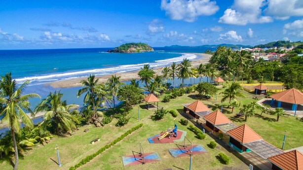 A resort with a beach view, palm trees, and a playground. - TOP OF VILLA IN ITS VERY GREEN (sainte marie)