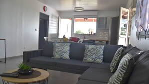 A modern living room with a sectional sofa, a coffee table, and a kitchen in the background. - TOP OF VILLA IN ITS VERY GREEN (sainte marie)