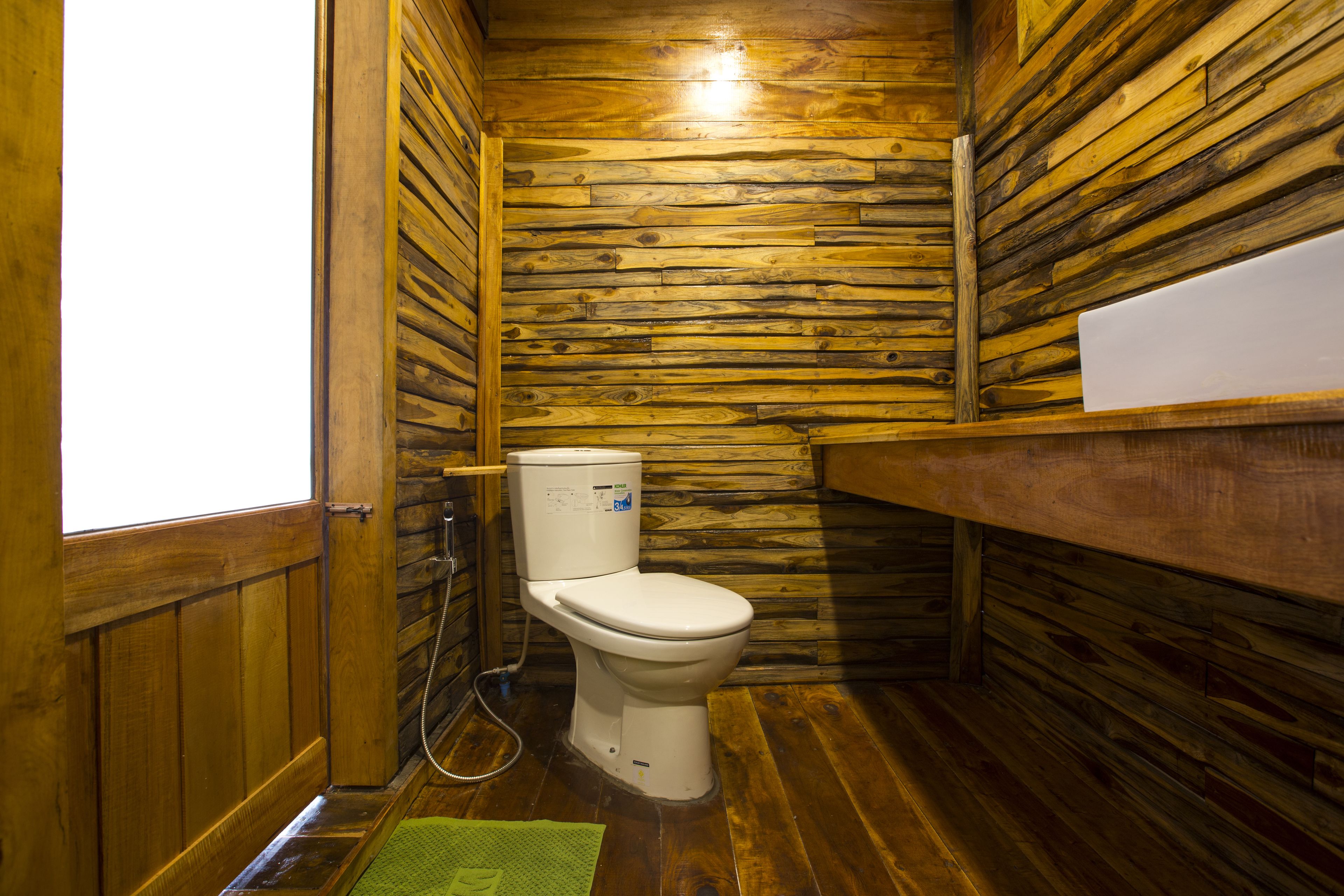 A wooden cabin bathroom with a toilet, shower, and wooden walls.