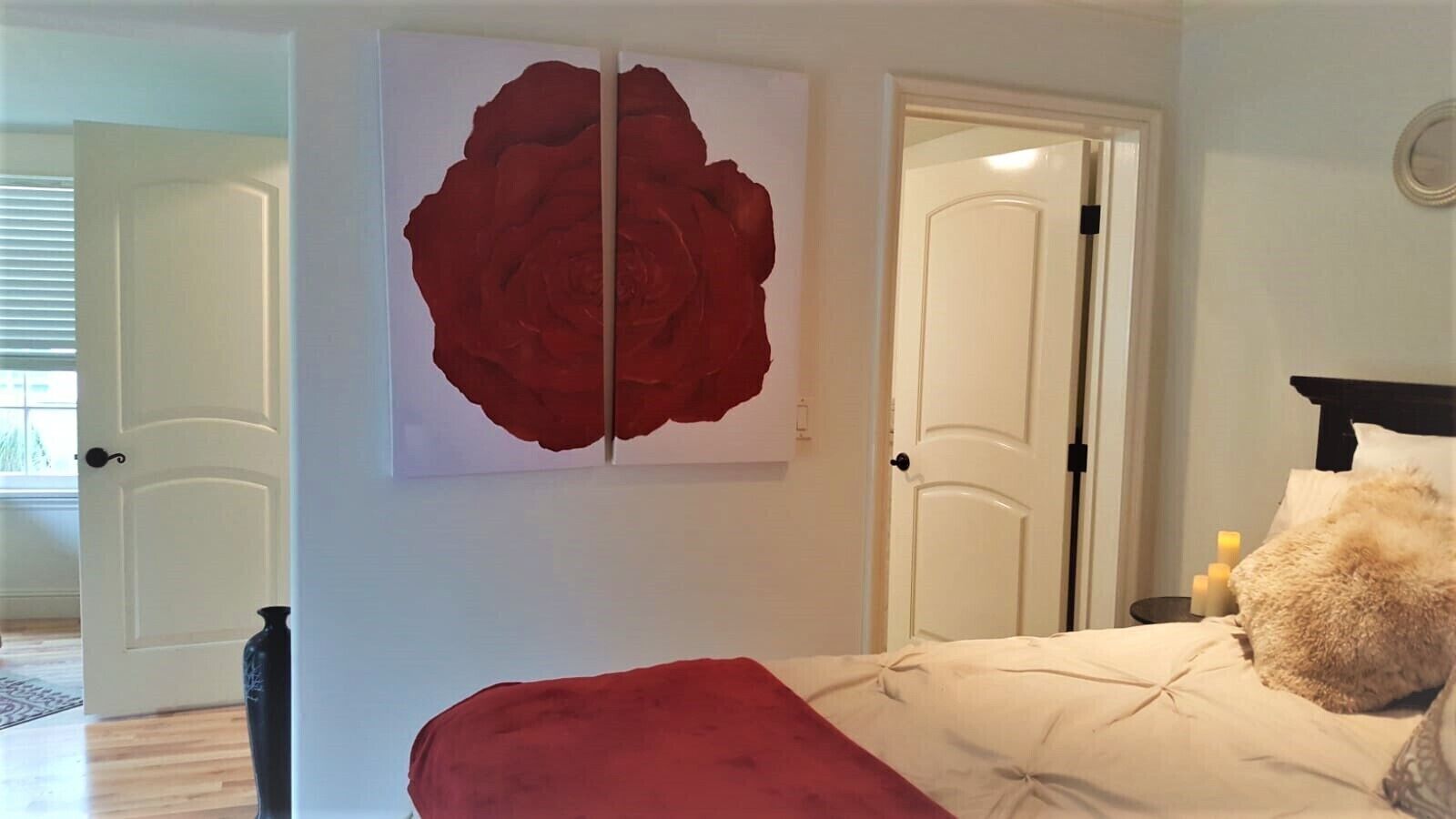 Une chambre avec un grand tableau abstrait rouge, un lit avec une tête de lit rouge et une porte blanche en arrière-plan.