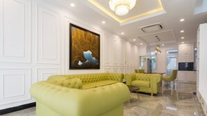 A modern living room with a sectional sofa, a dining area with chairs, and a kitchen in the background. - TOP#1 Experience Danang 'Casa de Tan 1' Pool Villa (Da Nang)