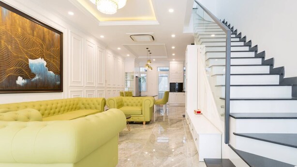 A modern living room with a staircase, a large abstract painting, and a dining area. - TOP#1 Experience Danang 'Casa de Tan 1' Pool Villa (Da Nang)