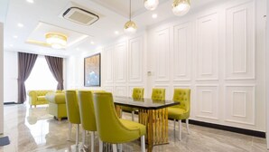A modern dining area with a black table and yellow chairs, white paneled walls, and a chandelier. - TOP#1 Experience Danang 'Casa de Tan 1' Pool Villa (Da Nang)