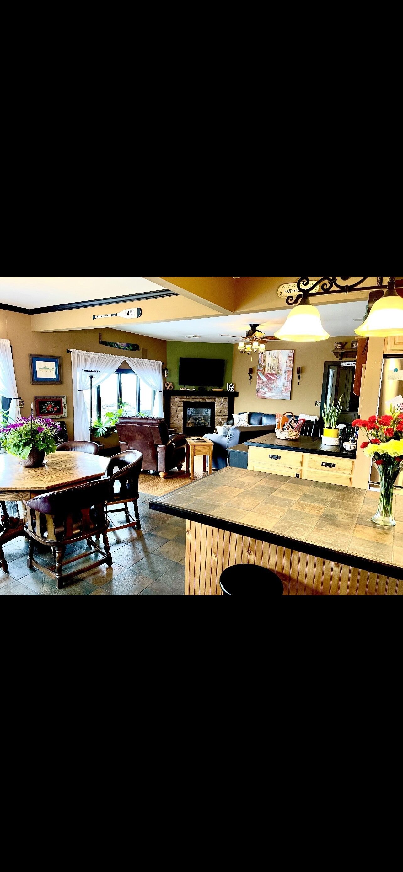Un vaste espace de vie doté d’une cheminée, d’une table à manger avec des chaises et d’un comptoir de cuisine.