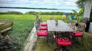 Une terrasse en bois avec une table et des chaises, donnant sur un lac.