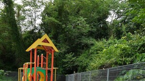 A playground with a seesaw, a slide, and a climbing structure. - Bosco Homestay (Kota Kinabalu)