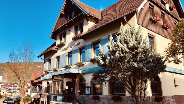A traditional Alpine-style hotel with a stone facade, wooden balconies, and a sign indicating it is a Landhotel. - Hotel Traube (Baden-Baden)