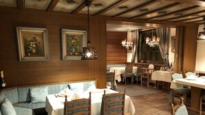 A restaurant with wooden paneling, a booth seating area, and a dining room with tables and chairs. - Hotel Traube (Baden-Baden)