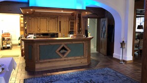 A kitchen with wooden cabinets and a central island, a blue rug on the floor, and a chandelier. - Hotel Traube (Baden-Baden)