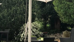 An outdoor seating area with wicker furniture and a table with a clear glass container. - Hotel Traube (Baden-Baden)