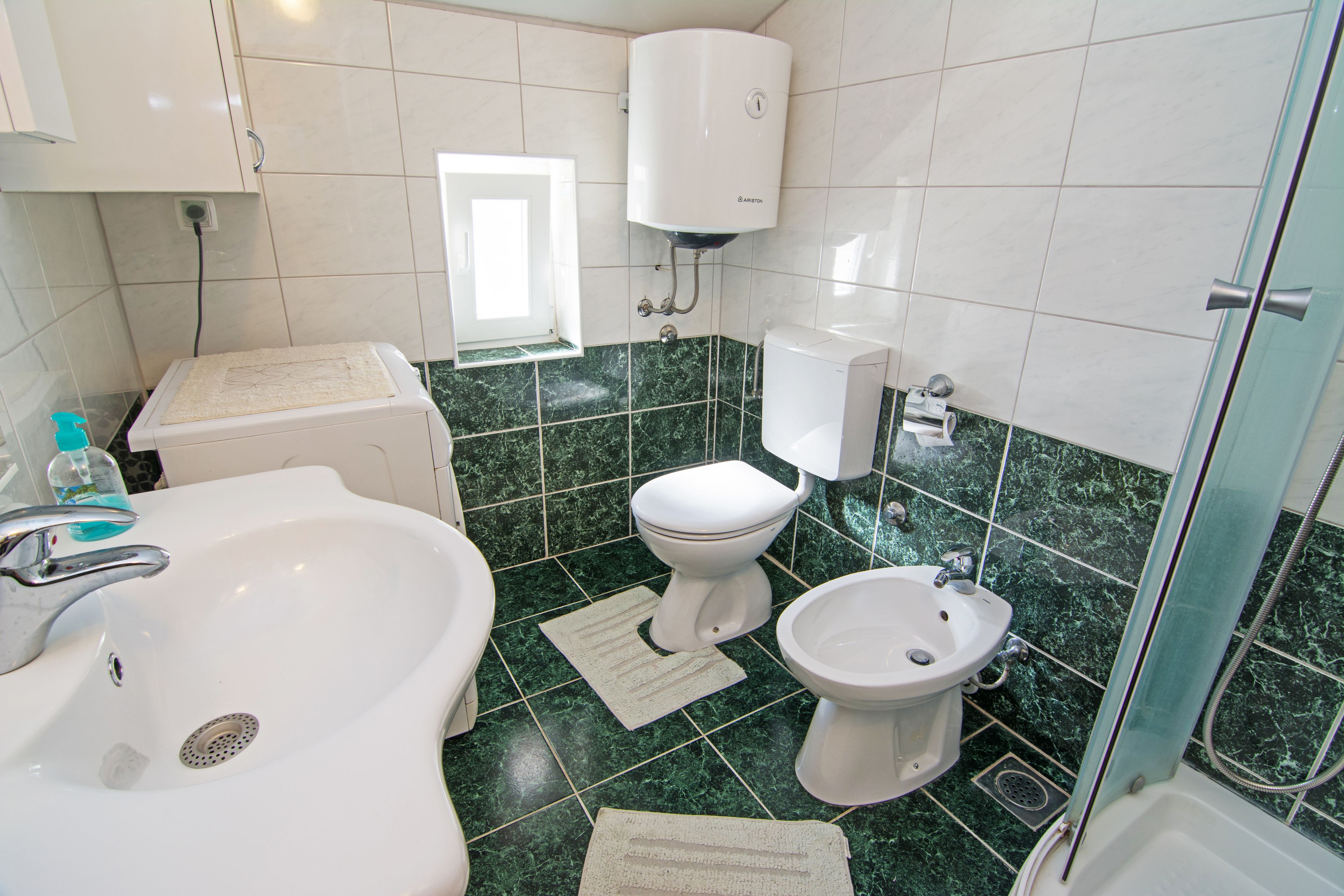 Un baño con lavamanos, inodoro, bidé y ducha.