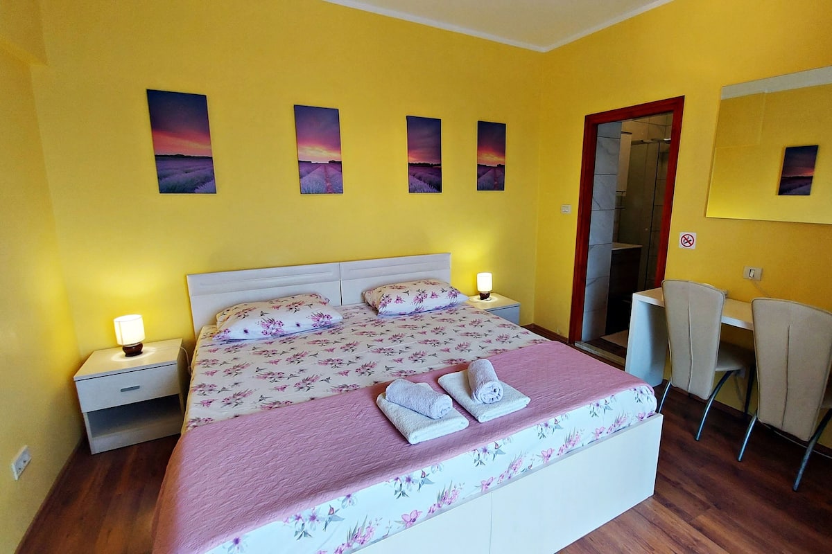 Ein Hotelzimmer mit Bett, Nachttischlampen, Schreibtisch, Stuhl und Dusche.