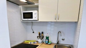 Una cocina compacta con microondas, pileta y alacenas.