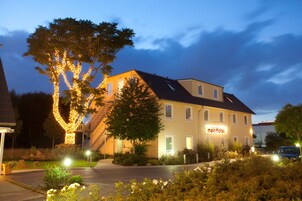 Ein Hotel mit einem Schild, auf dem 'meinHotel' steht, und ein mit Lichterketten beleuchteter Baum.