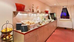 Zona de desayuno de hotel con barra libre, que incluye frutas, pan y bebidas.