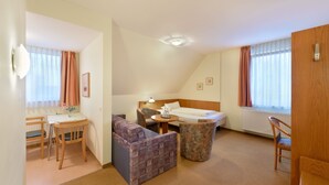 Una habitación de hotel con cama, escritorio, silla, sofá y una mesita.