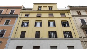Un immeuble à plusieurs étages, doté d’une façade jaune et de nombreuses fenêtres.