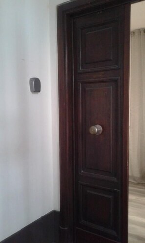 A dark wooden door with a silver handle, a small light switch on the wall, and a glimpse of a white curtain in the background. - B&B Holidays in Rome (Rome)