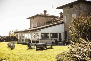 A stone building with a modern extension, outdoor seating, and a grassy lawn. - Agriturismo Al Castle (Montabone)