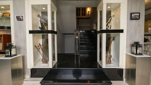 A staircase leading to a second floor with glass display cases containing musical instruments. - Maestro Hotel (Baku)