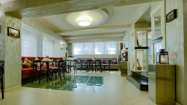 A spacious living area with a red sofa, black chairs, a glass coffee table, and a chandelier. - Maestro Hotel (Baku)