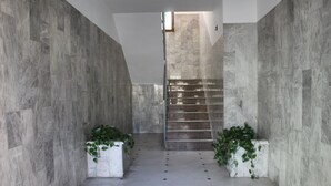 Un intérieur moderne avec un mur en pierre, un escalier et des plantes en pot.
