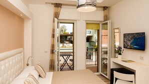 Une chambre avec un lit, un bureau et une télévision. Il y a un balcon avec une table et des chaises.
