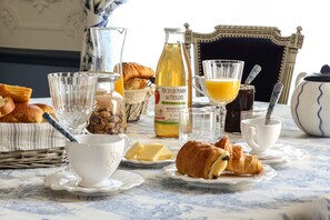 A breakfast setting with croissants, butter, jam, and orange juice on a table. - Domaine De Pouzelande B&B (Sanilhac)