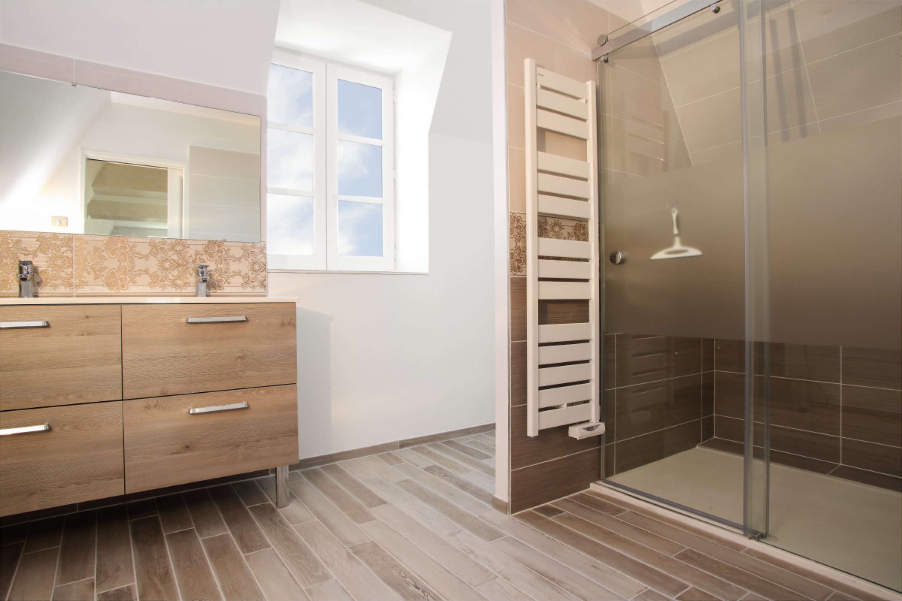A bathroom with a wooden vanity, a glass shower enclosure, and a window providing natural light.