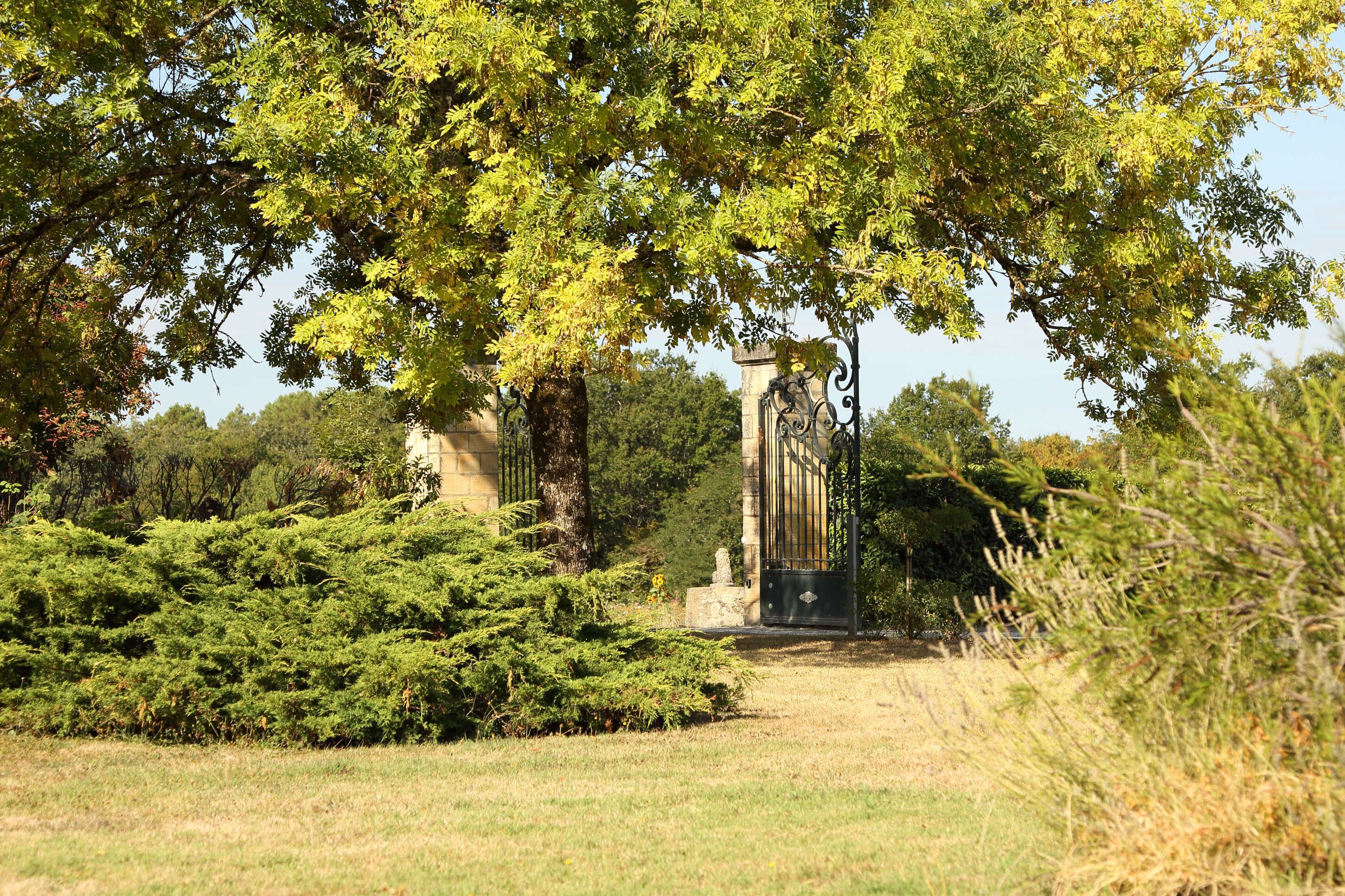 Un parc amb una estàtua, arbres i una construcció de pedra.