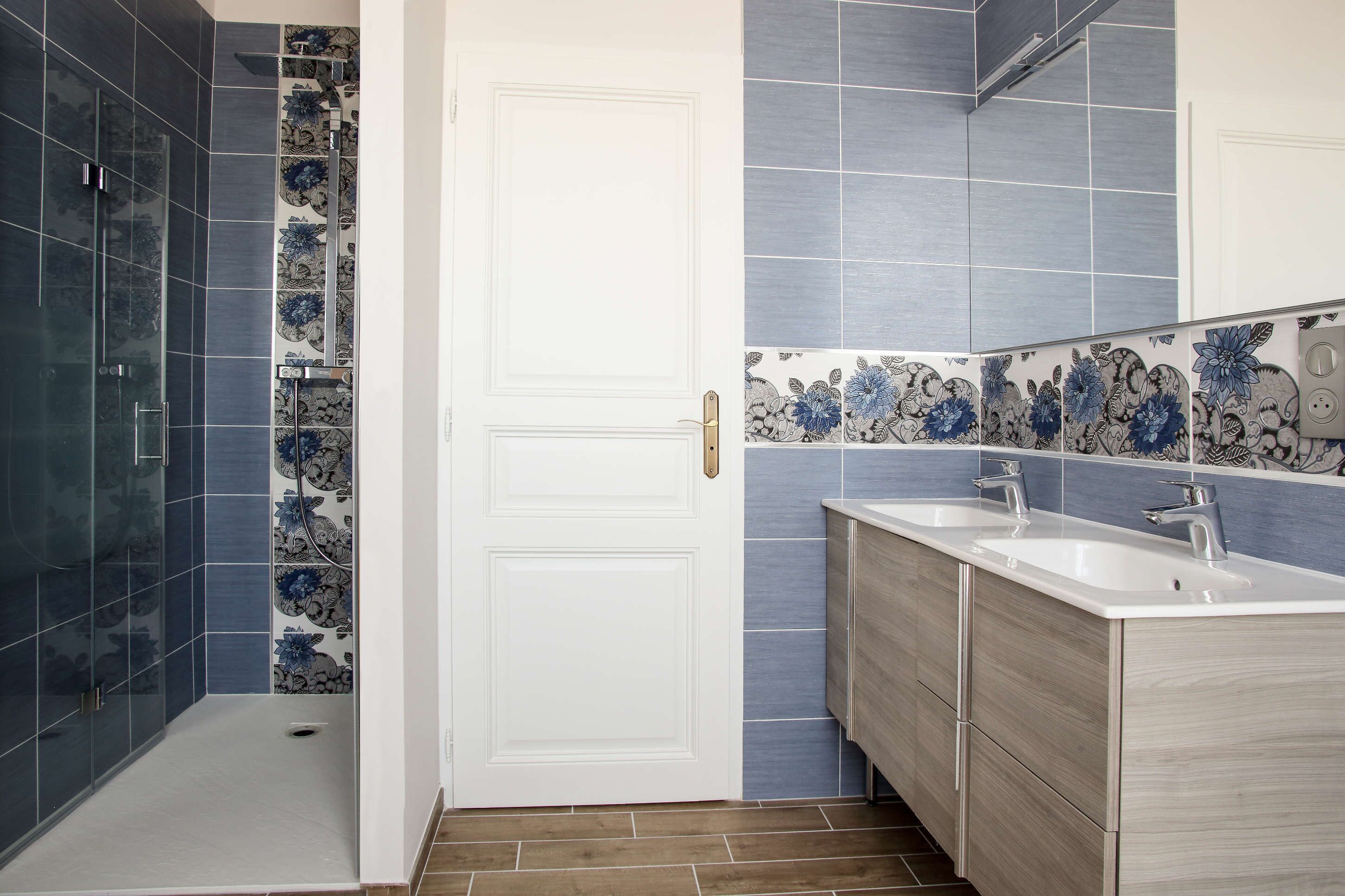 Een badkamer met een douche, twee wastafels en een spiegel.
