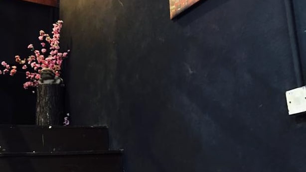 A staircase with a dark wall and a vase of pink flowers. - Cookoobird Home - Hostel (George Town)