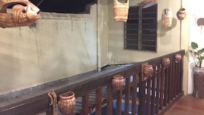 A wooden balcony with hanging pottery and a rustic railing. - Cookoobird Home - Hostel (George Town)