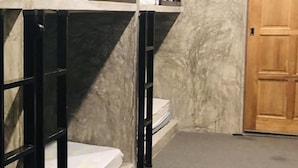 A room with bunk beds, a wooden door, and a marble wall. - Cookoobird Home - Hostel (George Town)