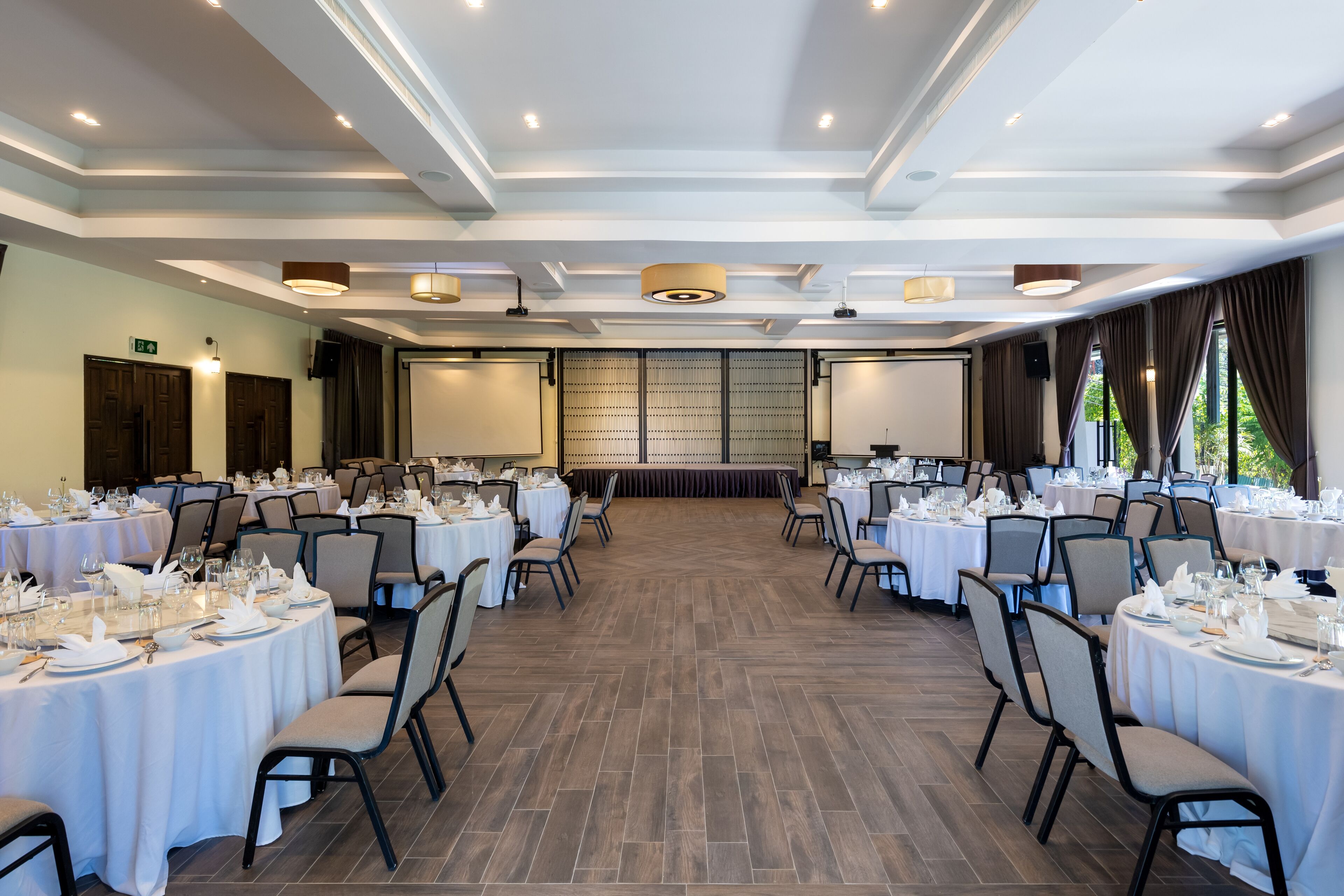 A conference room with round tables, chairs, and a stage.