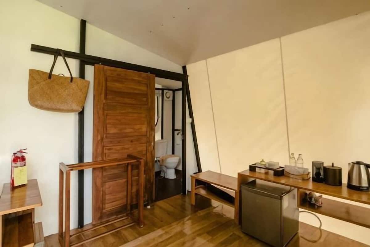 A compact kitchen with a wooden table, a small refrigerator, and a hanging basket.
