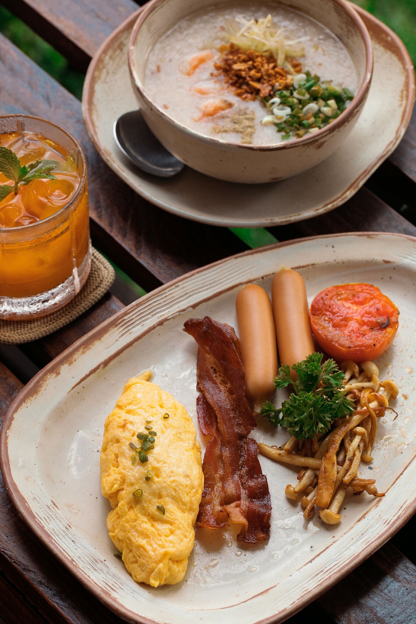 A breakfast plate with eggs, bacon, sausages, and a side of noodles.