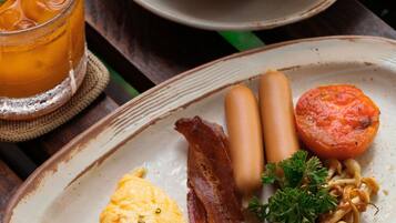 A breakfast plate with eggs, bacon, sausages, and a side of noodles.