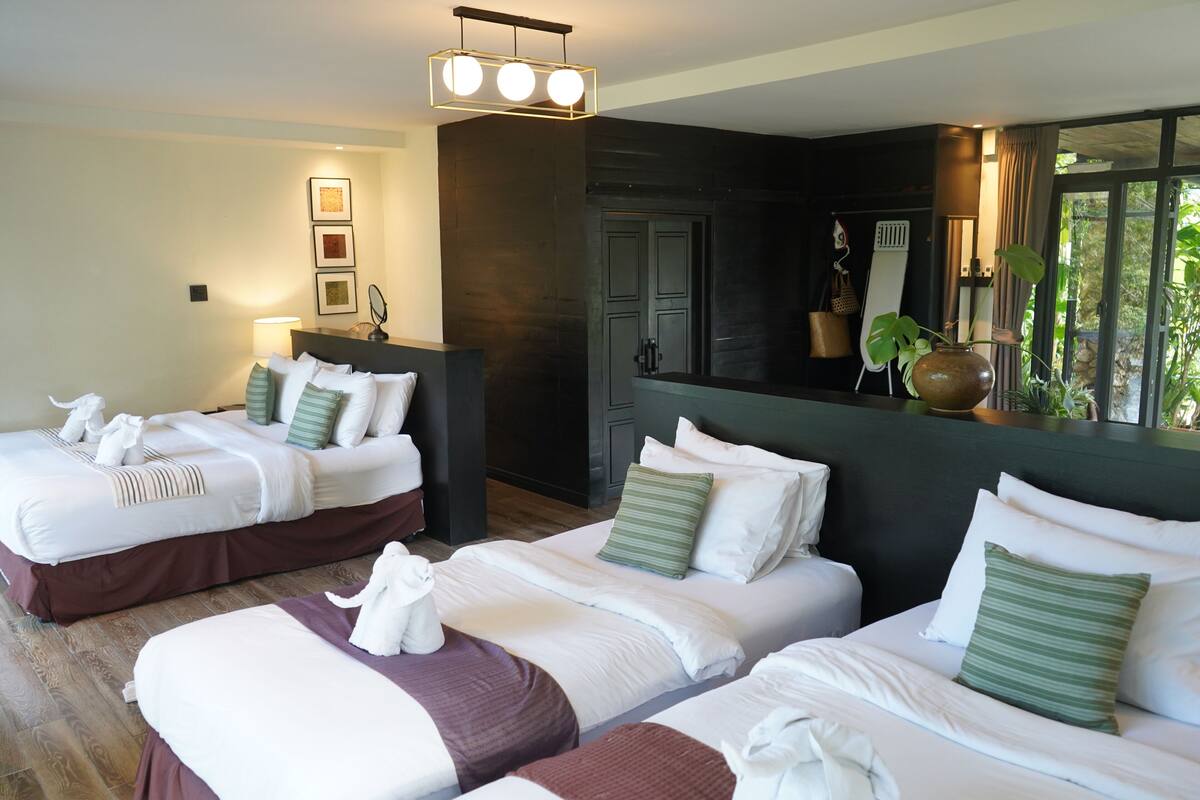 A hotel room with two beds, a large mirror, and a view of greenery outside.