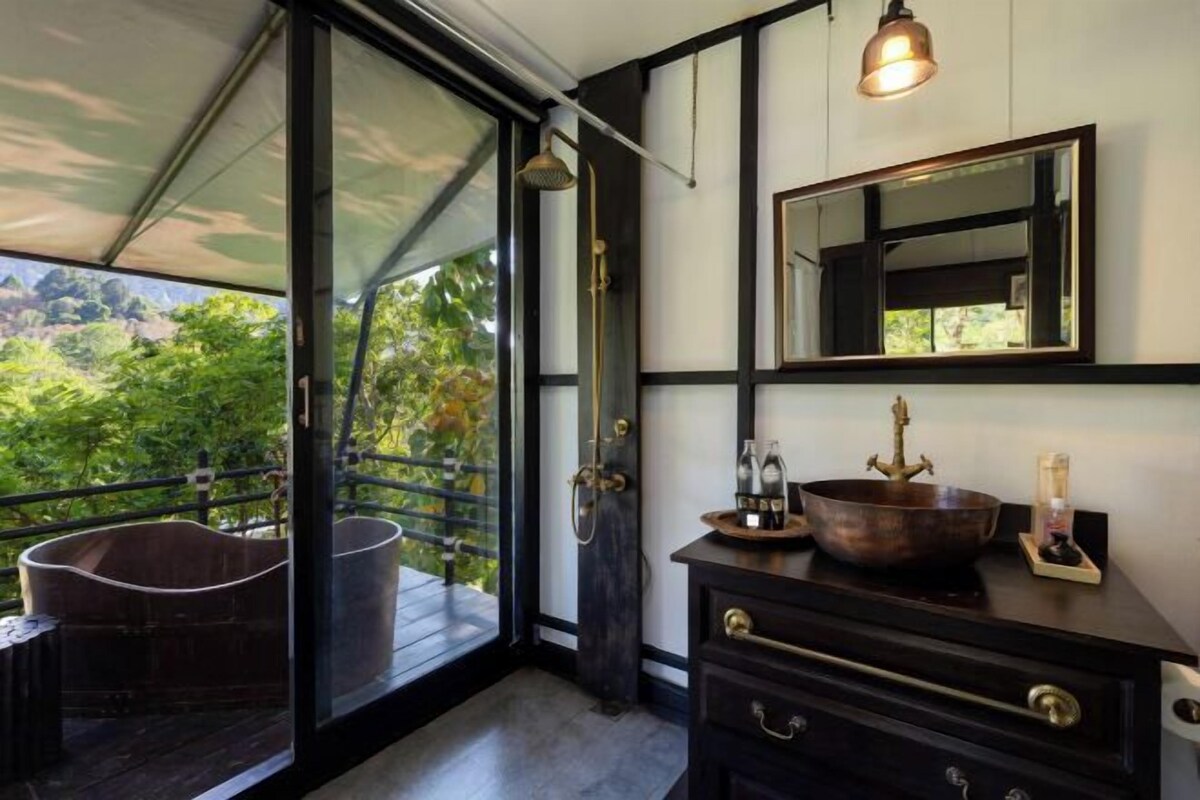 Un baño moderno con un espejo grande, un lavamanos con una pileta de cobre y una ducha con puerta de vidrio.