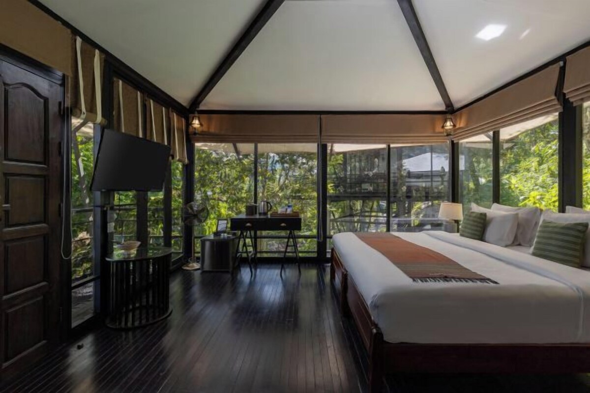 Ett sovrum med en säng, ett skrivbord, en stol och en tv.