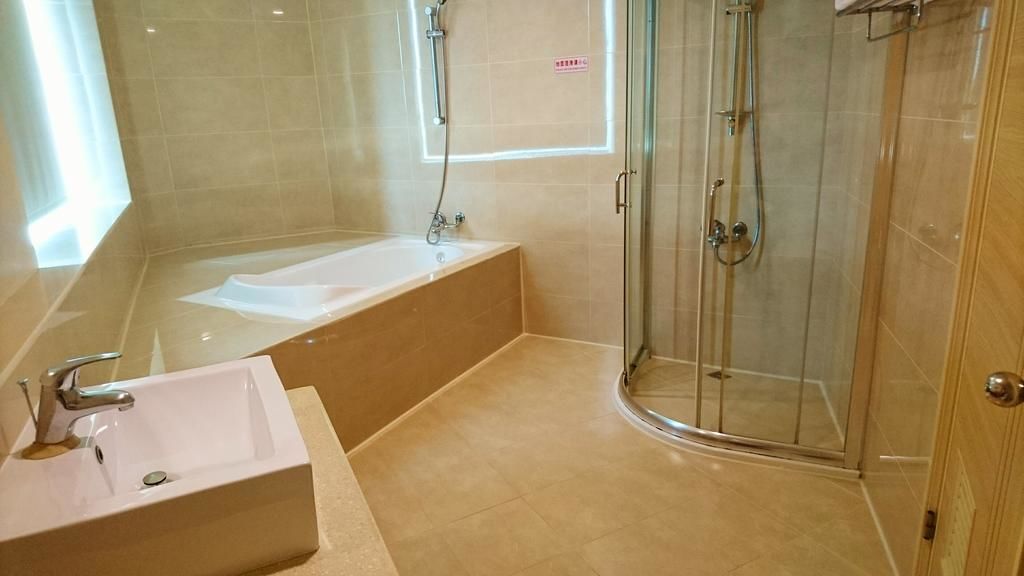 A modern bathroom with a bathtub, a glass-enclosed shower, and a sink.
