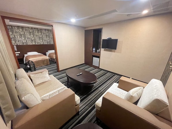 A hotel room with a sofa set, a small round table, a bed, and a television on the wall. - Metropolis Hotel (Taoyuan City)
