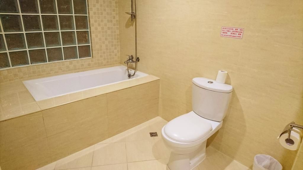 Een badkamer met een badkuip, toilet en een raam met uitzicht.